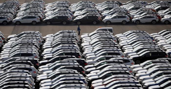 FILE PHOTO A worker is seen among newly manufactured cars awaiting export at port in Yokohama