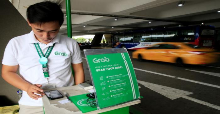 A Grab employee uses the Apps to book a cab for passengers at the Ninoy Aquino International