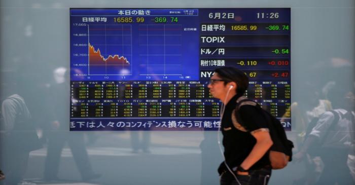 FILE PHOTO: A man walks in front of a screen showing today's movements of Nikkei share average