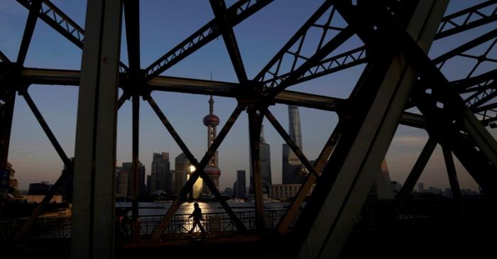 FILE PHOTO: A man walks on a bridge in front of the financial district of Pudong in Shanghai
