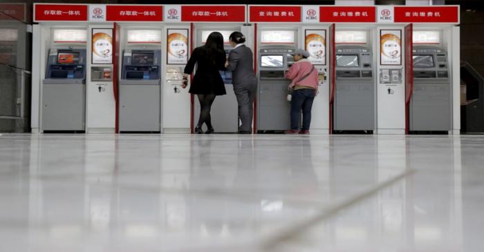 FILE PHOTO: A staff helps customers to use ATM at Industrial and Commercial Bank of China's