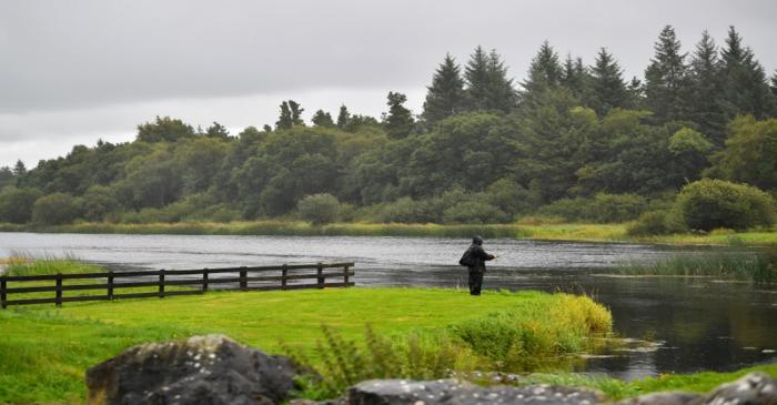 A man fishes in the rain on a river in Ballyforan