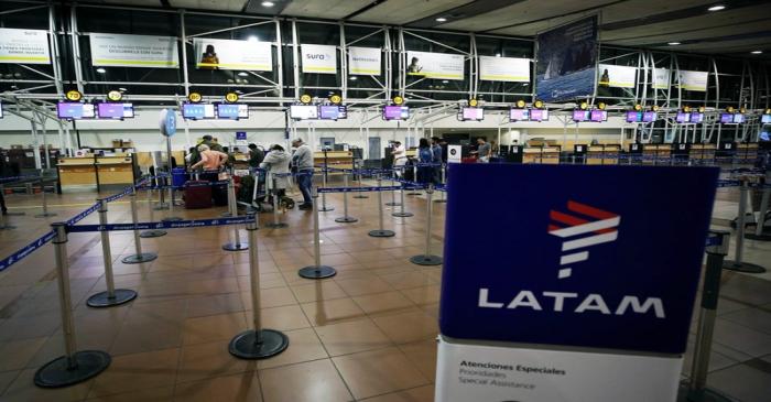 Passengers wait to check in for their flights at the departures area of Latam airlines inside