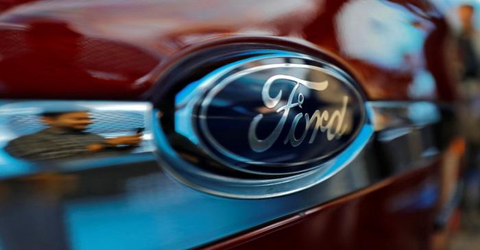 A visitor is reflected as he takes pictures of a new Ford Aspire car during its launch in New