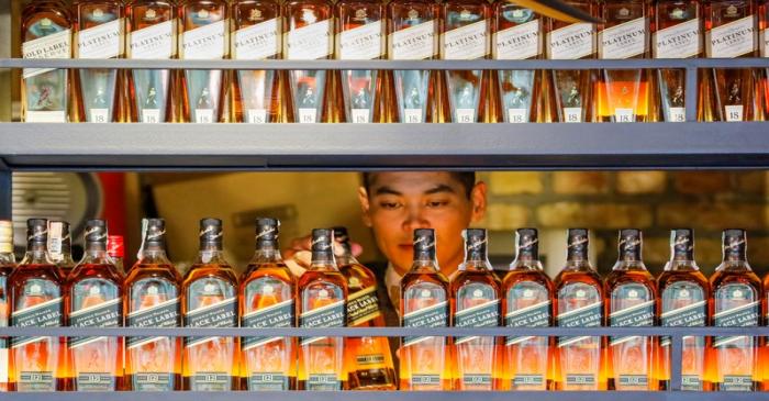FILE PHOTO: A bartender takes a bottle of Johnnie Walker whisky at Barmaglot bar in Almaty