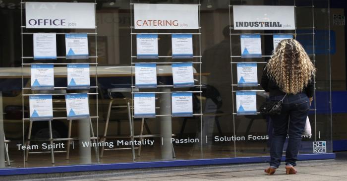 A woman looks at job advertisements in a window in Leicester, central England