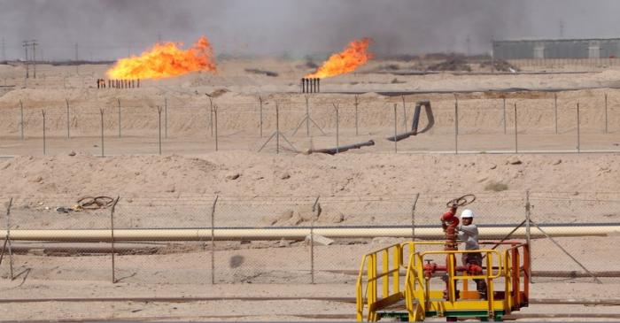 A worker adjusts a valve of an oil pipe in Zubair oilfield in Basra