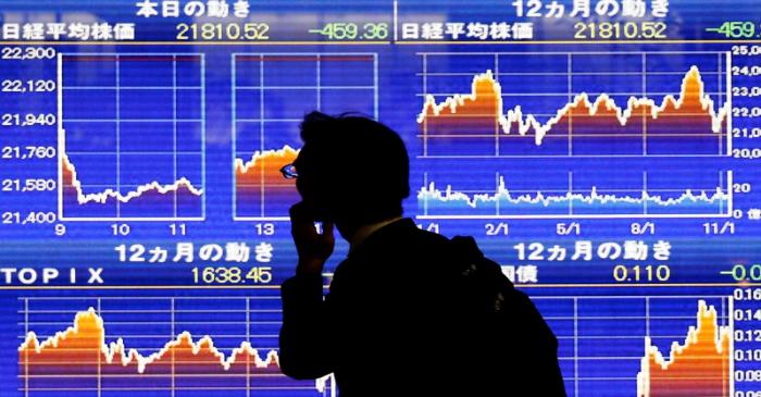 A man looks at an electronic stock quotation board showing Japan's Nikkei average outside a