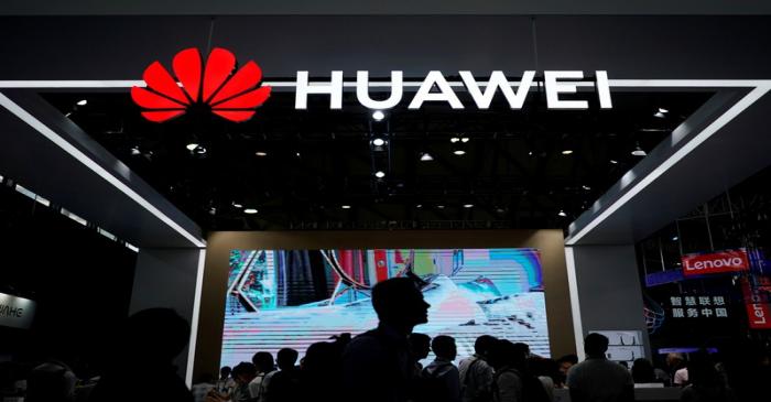 FILE PHOTO - People walk past a sign board of Huawei at CES (Consumer Electronics Show) Asia
