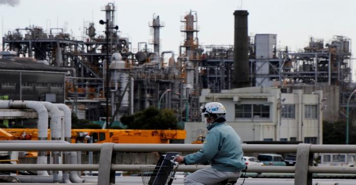 FILE PHOTO - Worker cycles near a factory at the Keihin industrial zone in Kawasaki,