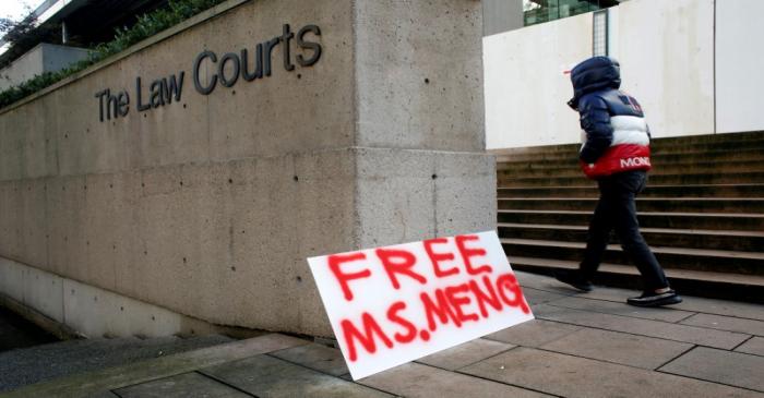 A man walks by a sign outside of the B.C. Supreme Court bail hearing of Huawei CFO Meng