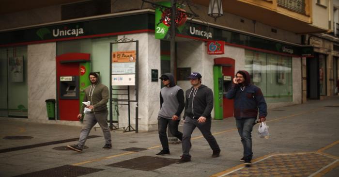 Tourists walk past a Unicaja bank branch at La Bola street in downtown Ronda