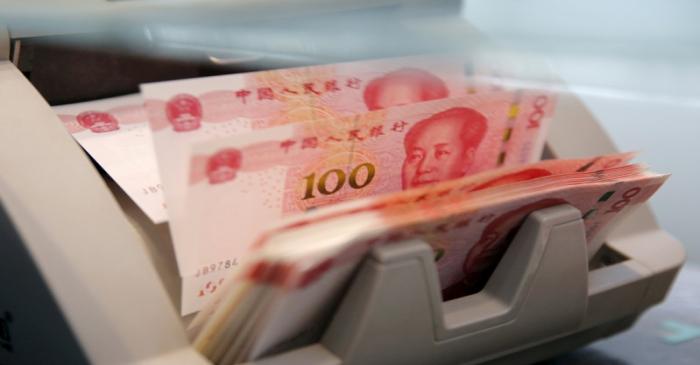 FILE PHOTO: Chinese 100 yuan banknotes in a counting machine while a clerk counts them at a