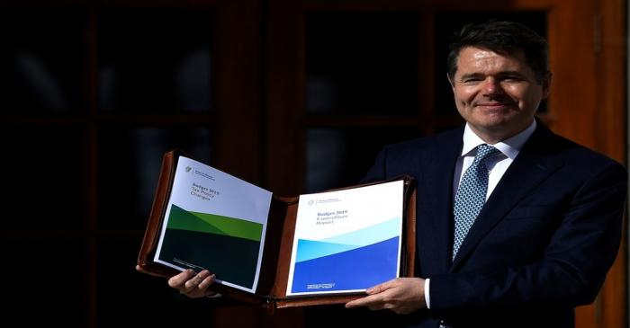 Ireland's Minister for Finance Paschal Donohoe displays a copy of the 2019 budget on the steps