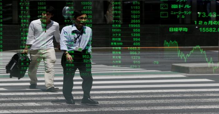 Passersby are reflected on a stock quotation board outside a brokerage in Tokyo, Japan