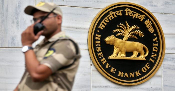FILE PHOTO: A guard stands next to the Reserve Bank of India (RBI) logo outside its