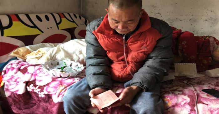 Wang Zhaohong holds his bankbook as he reviews the debt he owes in Sangzhi