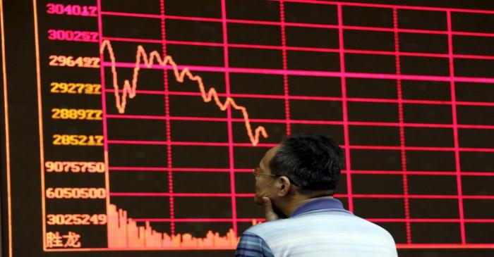 An investor looks at an electronic board showing stock information of Shanghai Stock Exchange