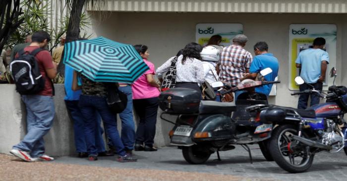 FILE PHOTO: People queue to withdraw cash from an ATM outside a BOD branch in Caracas