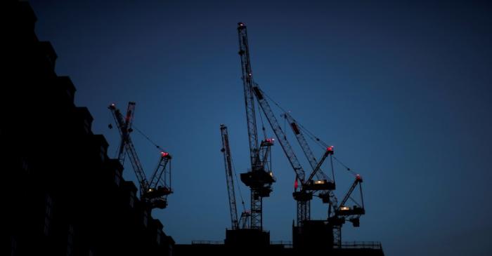 FILE PHOTO: Construction cranes are seen on a building site at sunrise in central London