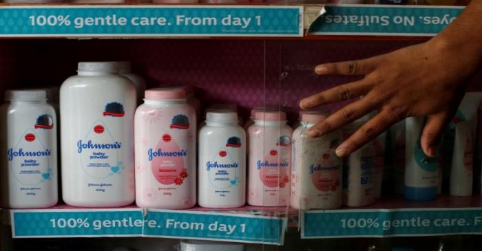 A worker closes a glass cabinet of Johnson & Johnson baby powder bottles at a medical store in