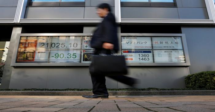A man walks past in front of a stock quotation board showing the price of the SoftBank Corp.