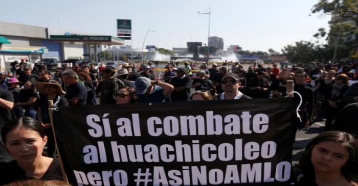 People hold a banner as they take part in a protest against fuel shortages near a gas station