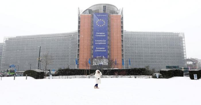 FILE PHOTO: A woman poses in front of the EU Commission headquarters as snow falls in Brussels