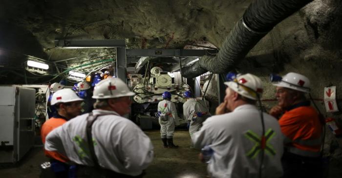 Mine workers are seen in front of a giant drill-cum-vacuum cleaner that accelerates drilling at