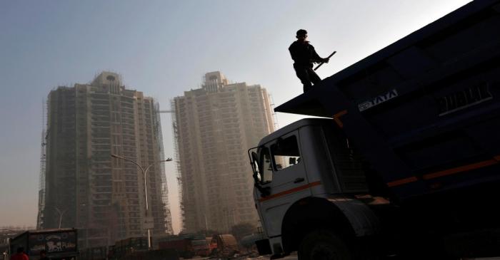 A labourer stands on a truck carrying construction materials at a construction site of