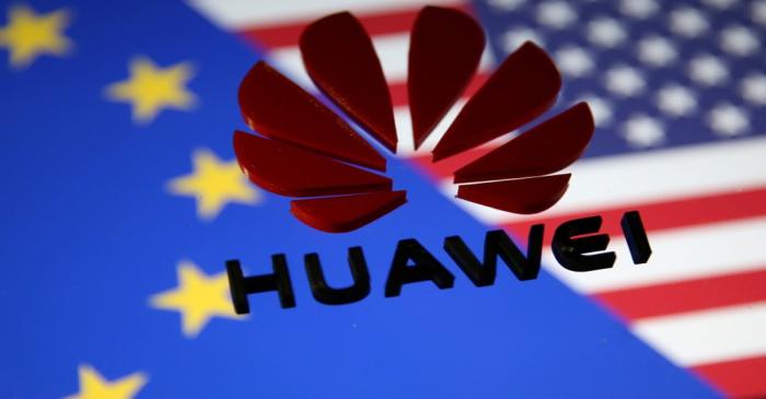 FILE PHOTO: A 3D printed Huawei logo is placed on glass above displayed EU and US flags in this
