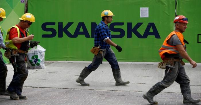 FILE PHOTO:  Workers walk past a Skanska logo seen on a fence at a construction site In Warsaw,