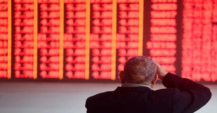 FILE PHOTO:  Man sits in front of an electronic board showing stock information at a brokerage