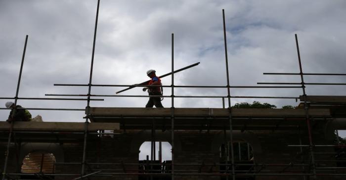 FILE PHOTO: A builder assembles scaffolding as he works on new homes in south London