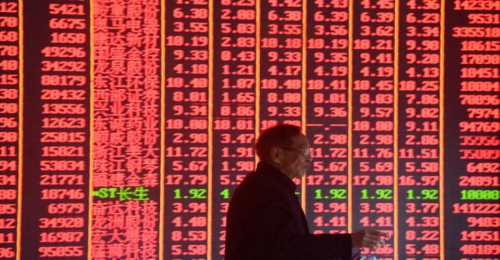 Man is seen in front of an electronic board showing stock information on the first day of