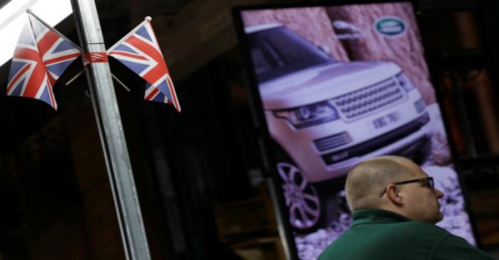 FILE PHOTO: A worker stands under Union Flags  at the Jaguar Land Rover facility in Solihull