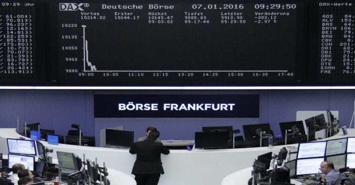 FILE PHOTO:  Traders work at their desks in front of the German share price index, DAX board,