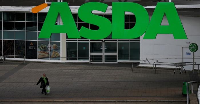 FILE PHOTO: An ASDA employee walks beneath a company logo outside a store in Manchester,