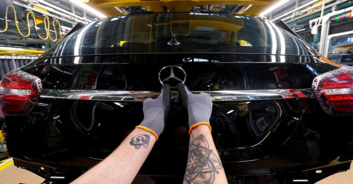 FILE PHOTO: An employee of German car manufacturer Mercedes Benz installs the characteristic