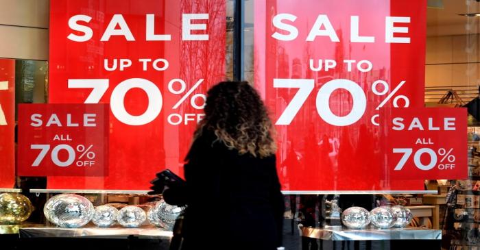 FILE PHOTO: A woman passes sale signs in a shop window in downtown Hamburg