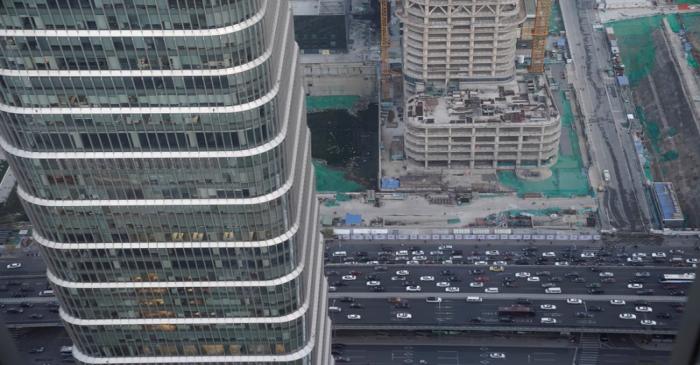 Cars drive past construction sites in Beijing's central business area