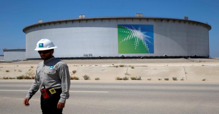 FILE PHOTO: An Aramco employee walks near an oil tank at Saudi Aramco's Ras Tanura oil refinery
