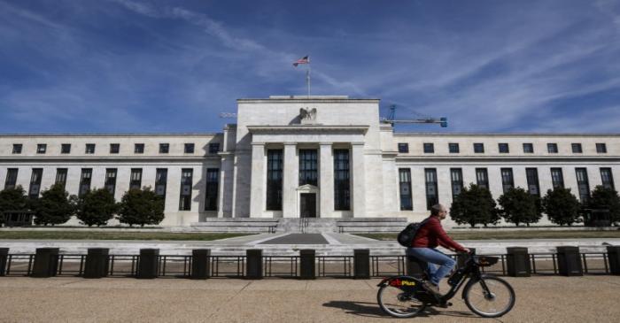 A man rides a bike in front of the Federal Reserve Board building on Constitution Avenue in