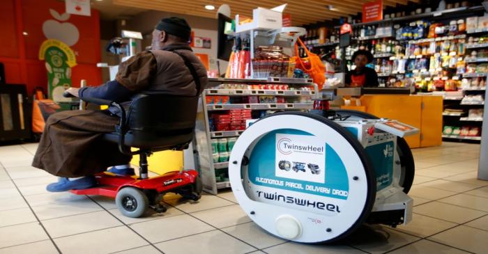 A man does his shopping at a store using an autonomous robot, shaped and inspired by Star Wars