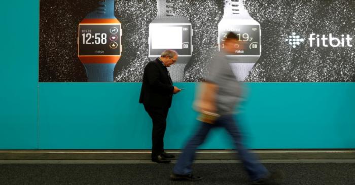 FILE PHOTO: Visitors walk past an advertising billboard for Fitbit Ionic watches at the IFA