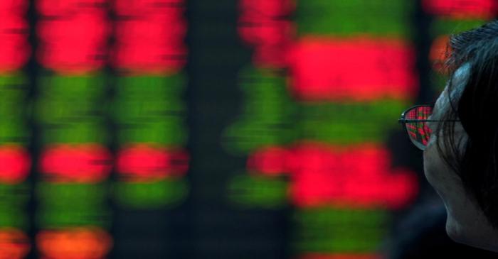 FILE PHOTO: An investor looks at an electronic board showing stock information at a brokerage