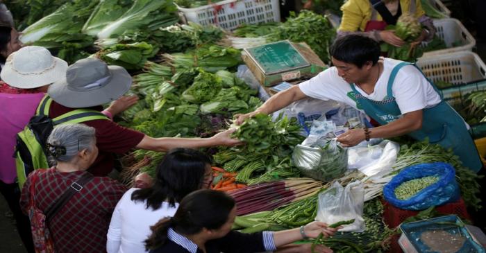 People shop for vegetables at a market in Kunming