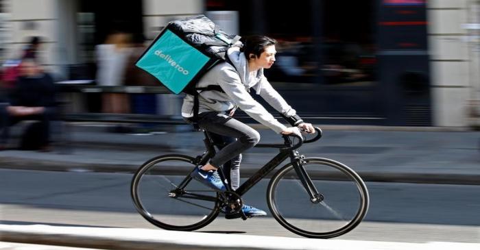 A cyclist rides a bicyle as he delivers food for Deliveroo, an example of the emergence of what
