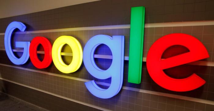 An illuminated Google logo is seen inside an office building in Zurich