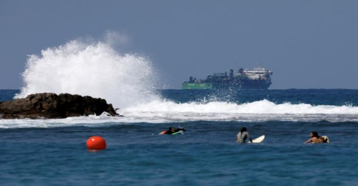 FILE PHOTO: People surf as a vessel involved in the construction of a natural gas pipeline is